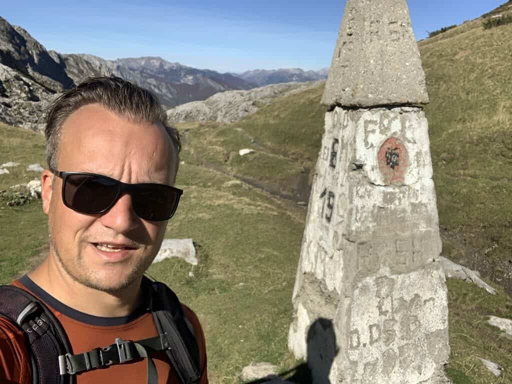 Balkan Trail - Border Permits - Border stone on the Pekas of the Balkans Trail with peaks in the background